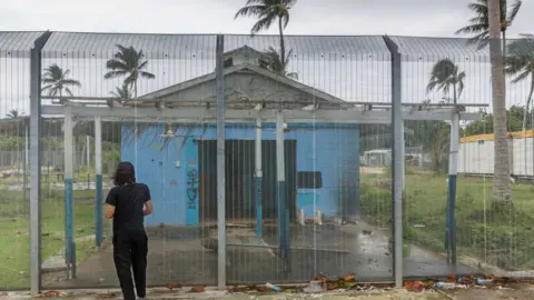 Getty Images Asylum seeker Behrouz Boochani, stands outside the abandoned naval base on Manus island, where he and other asylum seekers were locked up for the first three years.