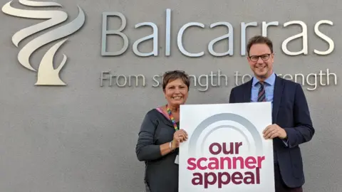 Gloucester Hospitals Charity A man and a woman holding a scanner appeal sign