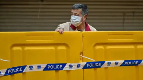 A man stands behind barriers during lockdown as a measure against the Covid-19 coronavirus in Shanghai.