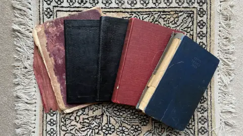 Saul Wordsworth Five battered hardback diaries spread out on a rug
