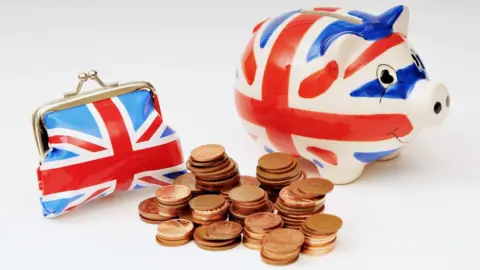 Getty Images A small purse and piggy bank in Union Jack colours with a pile of UK one and two pence coins