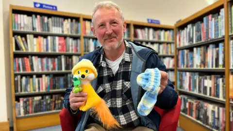 BBC Sergei Sogokon holding a knitted hat and toy fox