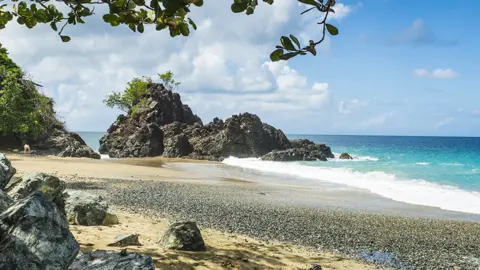 A general view of Turtle Beach, Tobago (also known as Courland Bay) showing sand, rocks, blue sea and sky