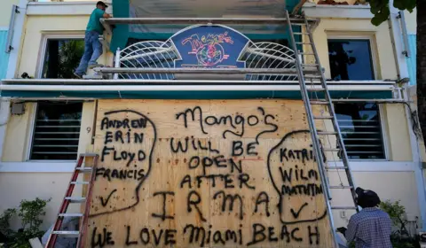 Reuters A worker covers the windows of a restaurant with plywood in preparation for Hurricane Irma, Miami Beach, Florida, 7 September 2017