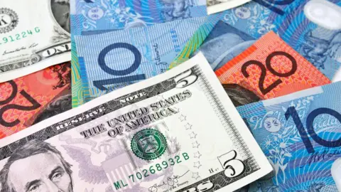 Getty Images A US $5 note sits on top of a stack of Australian currency