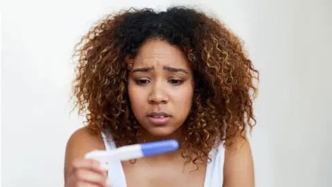 Getty Images Woman find out she is pregnant using a test