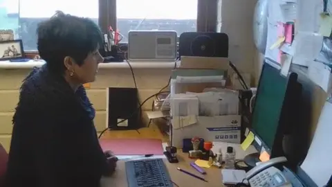 Cressida Sadler at her desk, using her computer