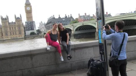 A man taking two women's photograph