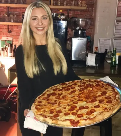 Kate Ovens holding extra extra large pizza