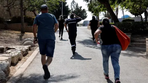 People run for shelter while sirens sound as rockets from Gaza are launched towards Israel, in Ashkelon, southern Israel.