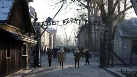 Reuters People walking through the infamous gate at Auschwitz, reading Arbeit Macht Frei - or work sets you free. File photo