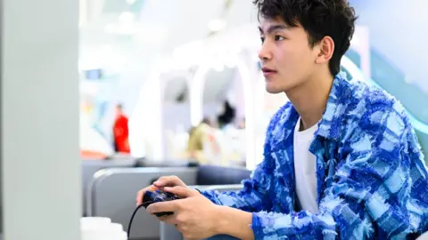 Getty Images Asian man playing a video game