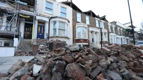 PA Media A roadside filled with debris from the rooftops of three houses which were torn off during storm Eunice, on Kilburn Park Road in north west London.