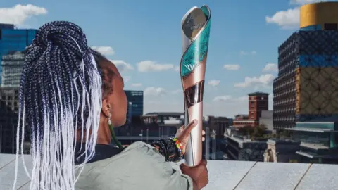 Birmingham 2022 Artist Laura Nyahuye holding the baton she designed