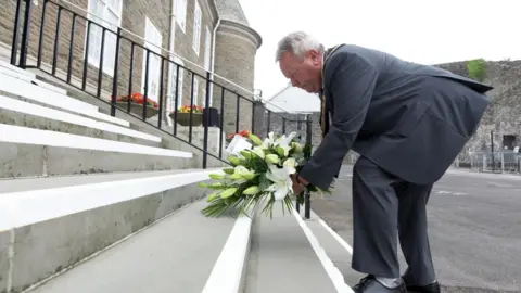 Carmarthenshire council David Parry Williams laying flowers on steps