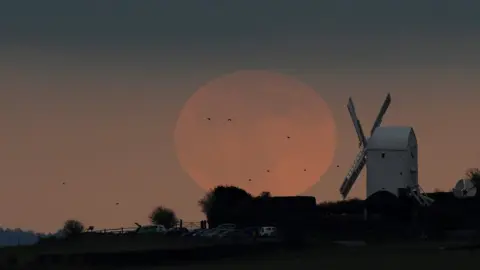 Reuters The full moon seen rising behind a windmill on the Sussex downs