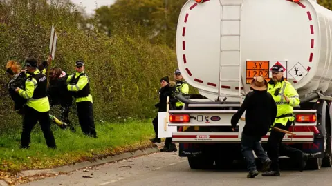 Getty Images Police officers restrain an anti-fracking protester attempting to stop a tanker lorry leaving the Preston New Road