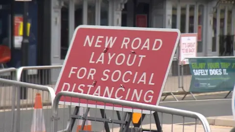 BBC A sign saying "new road layout for social distancing"