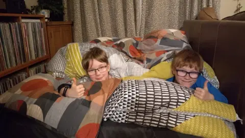 Jo Burtoft Two boys in duvets on sofa