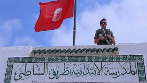 Getty Images A soldier stands guard on the roof of a polling station in Sousse, south of the capital Tunis, on September 15, 2019.