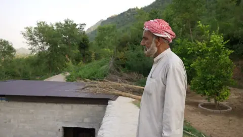 Raja Anwar stands on the roof of his home