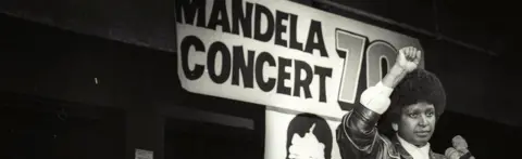 Reuters Winnie Mandela raises her fist in a black power salute after announcing that a massive pop concert will be held to mark the 70th birthday of her husband in 1988