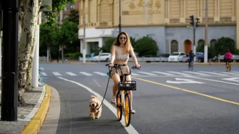 Reuters Image shows woman cycling with a dog
