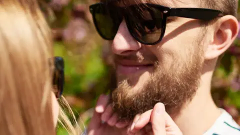 Getty Images Woman strokes a man's beard