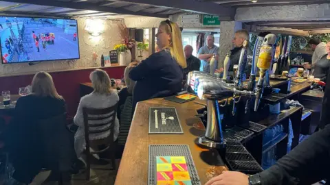 People in The Crown pub in Chinnor watching the Queen's funeral on a television