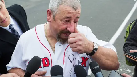 Getty Images A tearful former Ford employee speaks to reporters after a factory closure last year