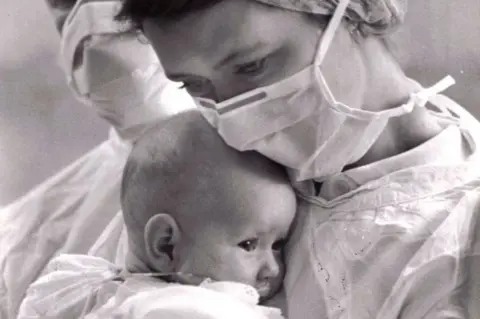 Carol Olley Carol holds baby Kaylee in hospital garb