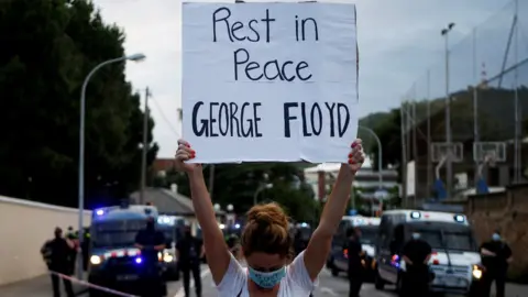 EPA A woman holds a sign reading "Rest in peace George Floyd" outside the US consulate in Barcelona