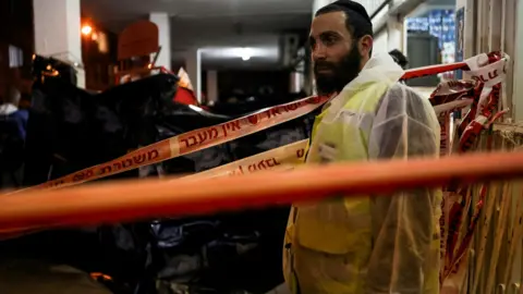 Reuters An Israeli police forensic expert pauses as he works at the scene of a fatal gun attack in Bnei Brak, Israel (29 March 2022)