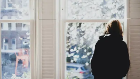 Getty Images A woman standing at a window (file image)