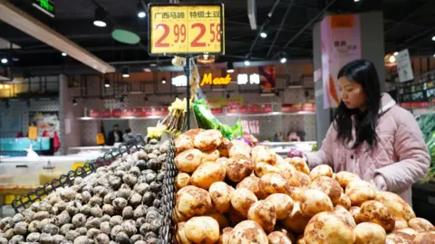 Getty Images A customer purchases potatoes at a supermarket on March 9, 2024 in Congjiang County, Qiandongnan Miao and Dong Autonomous Prefecture, Guizhou Province of China