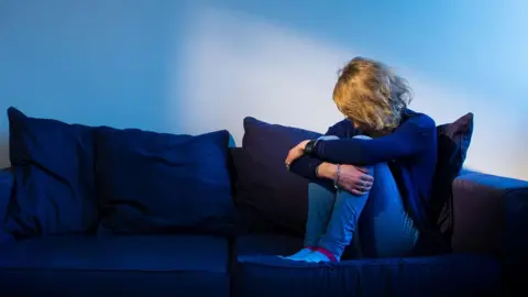 PA Media Woman sitting on a sofa
