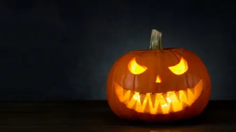 Getty Images A Halloween pumpkin with a scary face in a dark room