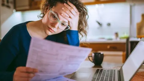 Getty Images Woman at desk with bill