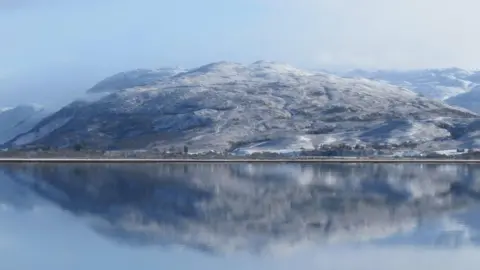 BBC Weather Watchers/Ingrid A snowy mountain reflects off water at Lochcarron in the Highlands