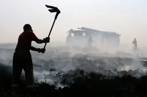 AFP Firefighters beat out wildfires on Winter Hill near Rivington in Lancashire, north west England on 1 July 2018.