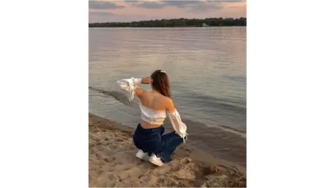 Teeanger girl crouching by river in Ukraine