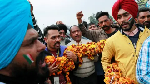 Reuters People hold a garland as they shout patriotic slogans before the arrival of Indian Air Force pilot, who was captured by Pakistan on Wednesday, near Wagah border, on the outskirts of the northern city of Amritsar, India, March 1, 2019