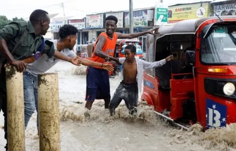 FEISAL OMAR/REUTERS A child is helped as he disembarks from a rickshaw taxi in a flooded road.