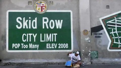 Getty Images Skid Row sign with man sitting underneath it