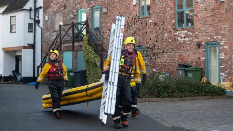 PA Media Fire and Rescue officers carry ladders and an inflatable raft in Bewdley, Worcestershire,