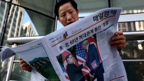 Getty Images A man in South Korea reads a newspaper carrying images of the summit