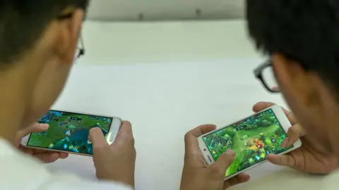 Getty Images Young players practice the mobile game Arena of Valor, prepared for the battle match held in a shopping mall. Arena of Valor: 5v5 Arena Game, China's most popular mobile game developed by Tencent Inc, which is the world's largest mobile games developer.