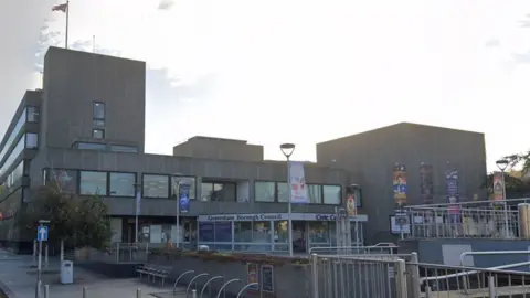 Google A large concrete building with Gravesham Borough Council written across the front and the sun shining from behind it