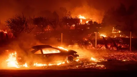 AFP/Getty Vehicles and homes burn as the Camp fire tears through Paradise, California