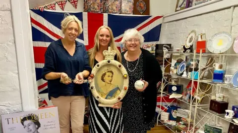 PA Media Pip Jeyes, Anna Jeyes-Hulme and Georgina Jeyes in front of memorabilia at the Royal Room at Jeyes of Earls Barton in Northamptonshire, which was launched in 2012.